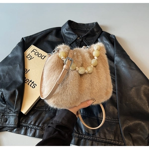 Detailed close-up of faux mink fur bucket bag with cream beaded handle and leather strap