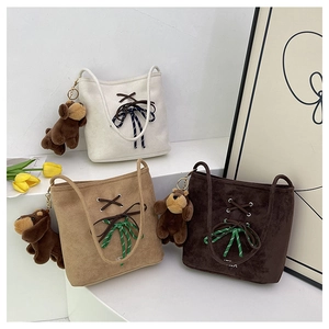 Close-up of suede bucket bags in beige and brown with bow details and dog charms