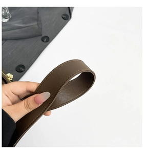Detailed close-up of dark brown leather strap with stitching and gold metal buckle