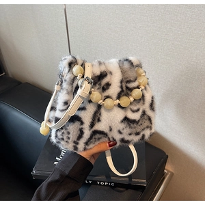 Detailed view of leopard print faux fur bag with beaded handle and white leather strap