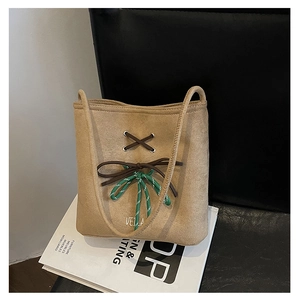 Detailed shot of camel suede shoulder bag with woven rope bow and polished texture