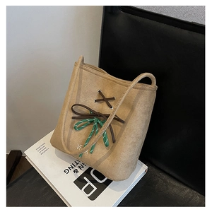 Detail of khaki suede tote bag featuring leather lacing and a decorative woven bow