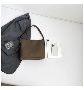 Flat lay of brown matte faux leather bucket bag with gold lettering and size reference