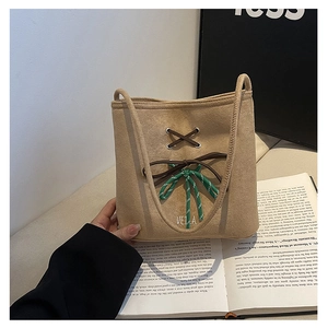 Detailed view of beige suede bag with decorative brown lacing and woven rope accent