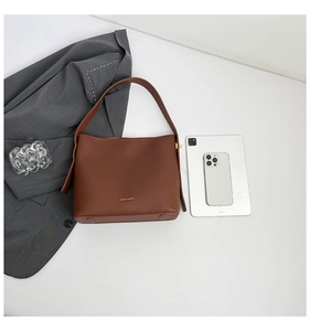 Brown leather tote bag size comparison with tablet and phone for daily commute use