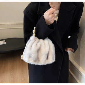 Close-up of light gray faux fur bag with elegant marble beaded handle on black coat