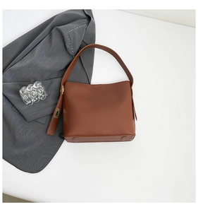 Detailed view of brown bucket bag bottom with protective feet and gold buckle detail