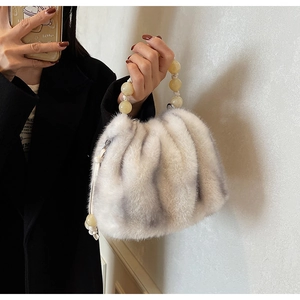 Detail of faux fur cloud bag featuring plush texture and large beaded carry handle
