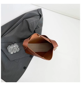 Overhead detail of brown bucket bag interior showing gold magnetic closure and lining