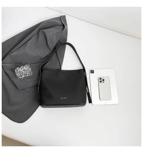 Detail view of black leather bucket bag next to a tablet showing interior storage capacity