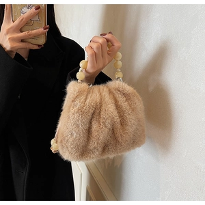 Detailed view of brown faux fur bucket bag featuring a large yellow bead handle