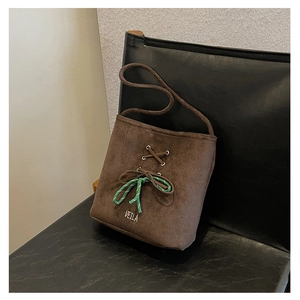 Detailed macro view of dark brown suede bucket bag with green decorative rope bow