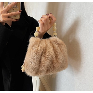 Detail of faux fur bucket bag with beige bead handle and pleated plush texture