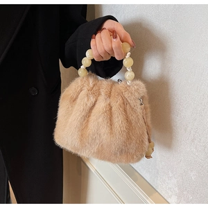 Detail of faux fur bucket bag with amber beaded handle and soft plush texture