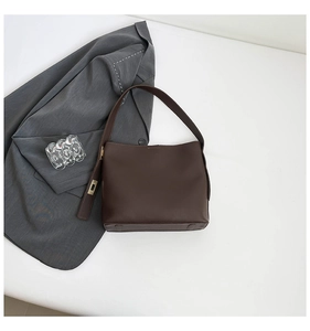 Detailed macro view of smooth dark brown leather tote bag with wide integrated shoulder strap