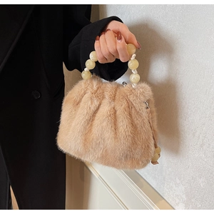 Detail of faux fur bucket bag with amber beaded handle and soft plush texture