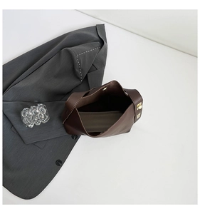 Detail view of large dark brown leather tote bag with elegant gold hardware for business use
