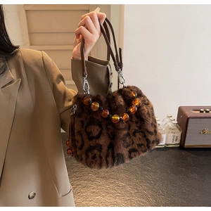 Close-up of leopard print faux fur bucket bag with amber bead handle and leather strap