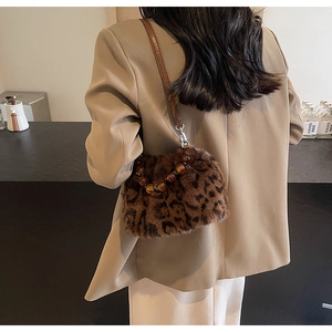 Detail of leopard faux fur bucket bag with a brown leather strap and amber bead charm