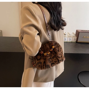 Detail of leopard print faux fur bucket bag featuring amber beaded handle and slim strap