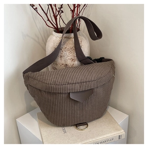 Detail of coffee corduroy crossbody bag with adjustable strap on a white surface