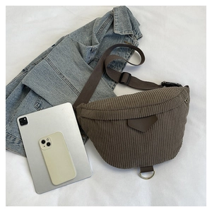 Detailed view of brown corduroy sling bag showing texture with tablet and phone for scale