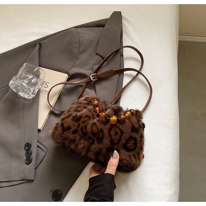 Detail of leopard print faux fur bucket bag with amber bead handle and leather strap