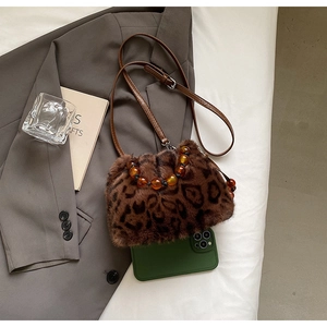 Detail of leopard print faux fur bucket bag with beaded handle and leather strap