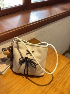 Chic cream faux suede bucket bag with decorative lacing and a plush dog charm