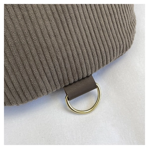 Detail of brown corduroy fabric and leather loop with gold metal D-ring on a casual bag