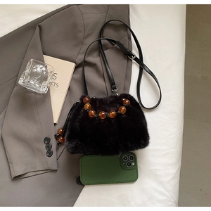 Detail of black faux fur bucket bag with amber beaded handle and leather strap