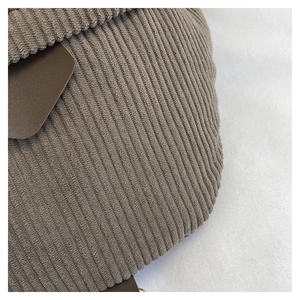 Detailed macro view of brown corduroy fabric texture and premium leather flap trim