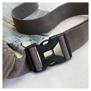 Close-up of durable gray corduroy strap with black plastic buckle on denim background