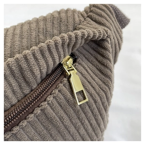 Detailed macro view of dark brown corduroy fabric and golden metallic zipper