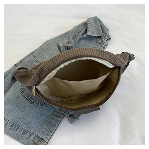 Detail view showing interior compartment and brown corduroy fabric of the belt bag