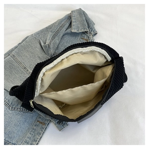 Interior view of black corduroy bag with beige lining and internal storage pocket
