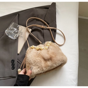 Detail of beige faux fur handbag with amber beaded handle and leather shoulder strap