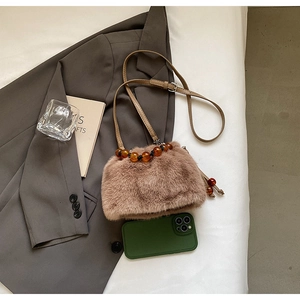 Detail of plush faux fur bucket bag featuring amber beaded handle on a brown blazer
