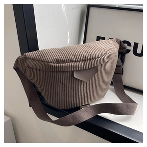 Detail of minimalist corduroy waist bag showing texture, leather patch and buckle strap