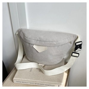 Close-up of light gray corduroy waist bag with adjustable strap on art books