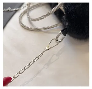 Détail de la chaîne argentée et de la sangle en strass avec mousquetons sur sac en fausse fourrure