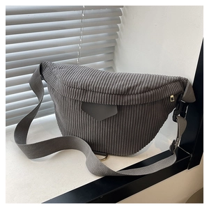 Detail of dark grey corduroy crescent chest bag with adjustable strap on white windowsill