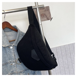 Detail of black corduroy crossbody bag with adjustable strap and metal ring on a rack