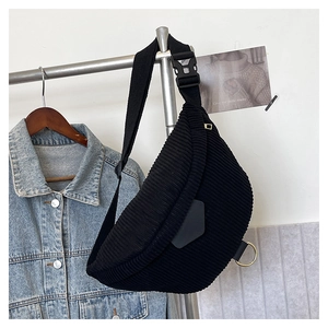 Detailed close-up of a black corduroy moon-shaped chest bag with golden ring decor