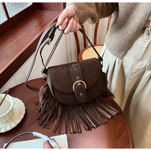 Detail of vintage brown suede saddle bag with fringe tassels and gold horseshoe buckle