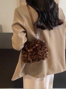 Leopard print faux fur bucket bag with amber beaded handle on tan suit model