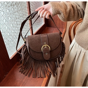 Detail of dark brown vintage saddle bag with long tassels and large gold buckle