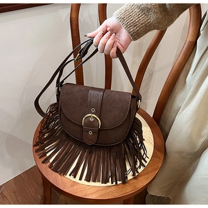 Detail of vintage brown tassel saddle bag with gold ring buckle on a woven chair