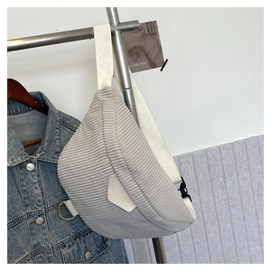Detail of light gray corduroy cross-body bag with ribbed texture and white strap