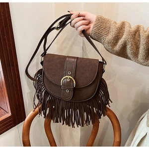 Detail of vintage brown tassel saddle bag with matte finish and adjustable strap